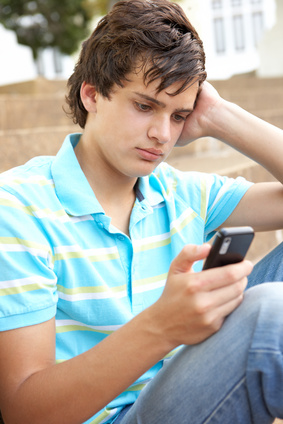 Unhappy Male Teenage Student Sitting Outside